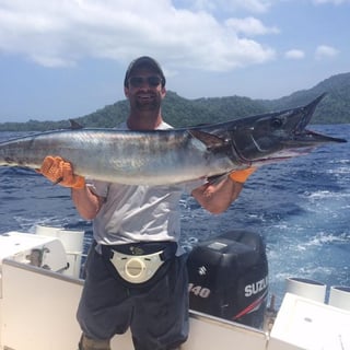 Mike on a fishing boat holding a very large fish. 