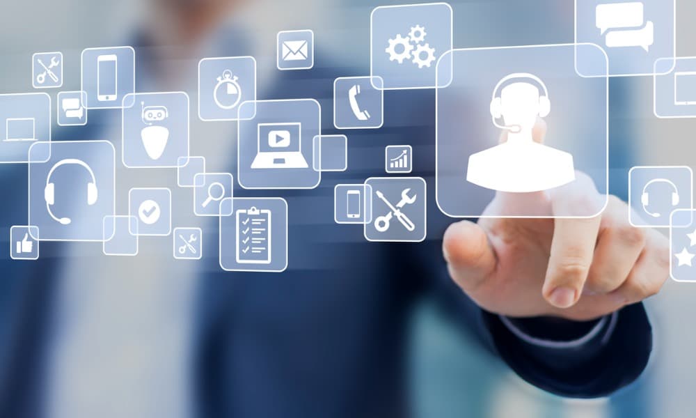 A businessman clicks a customer service icon on a screen. Other icons in the image include those for email, chat, phone, and tools.